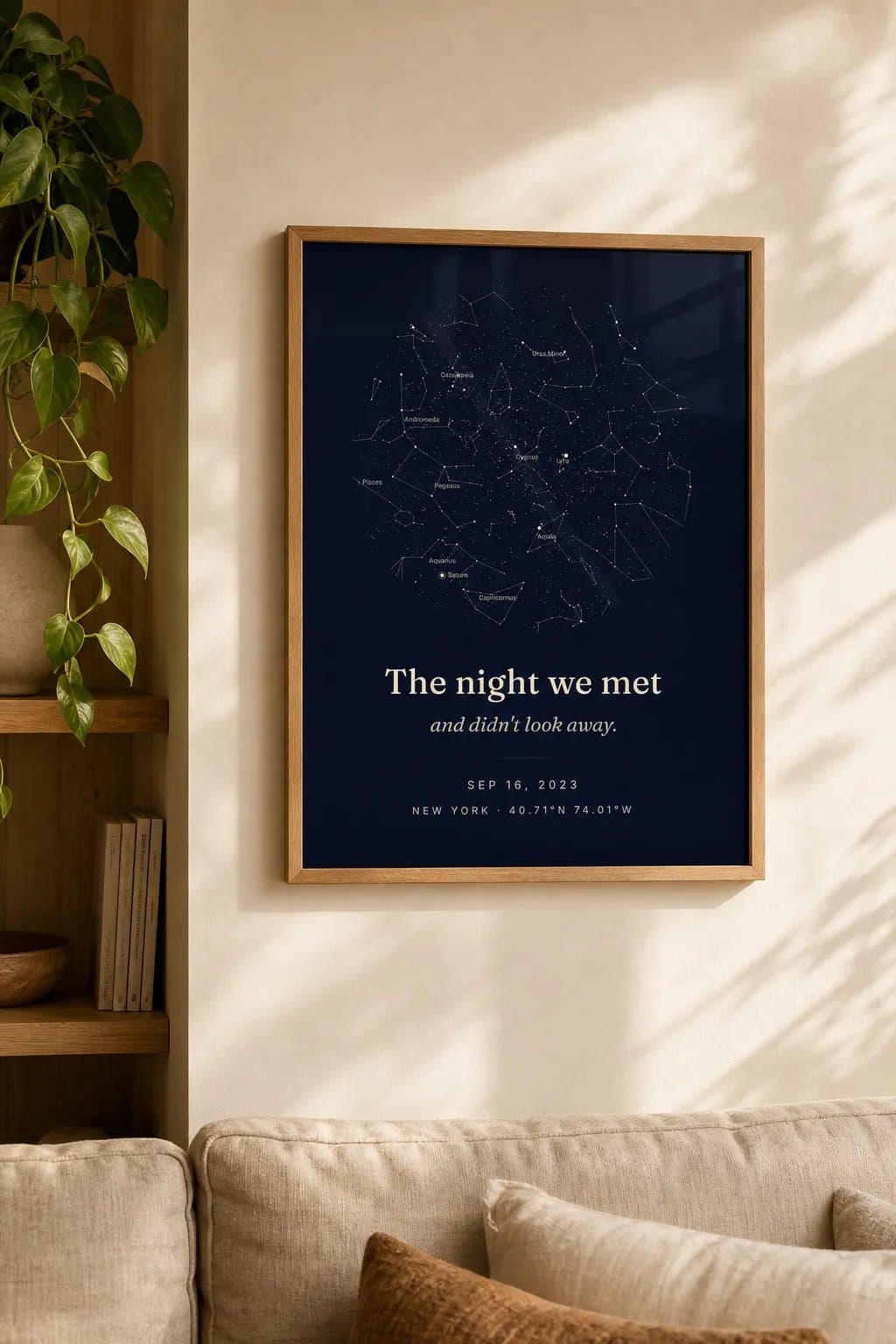 A framed navy star map titled The night we met, and didn't look away, hanging on a warm white wall above a sofa.