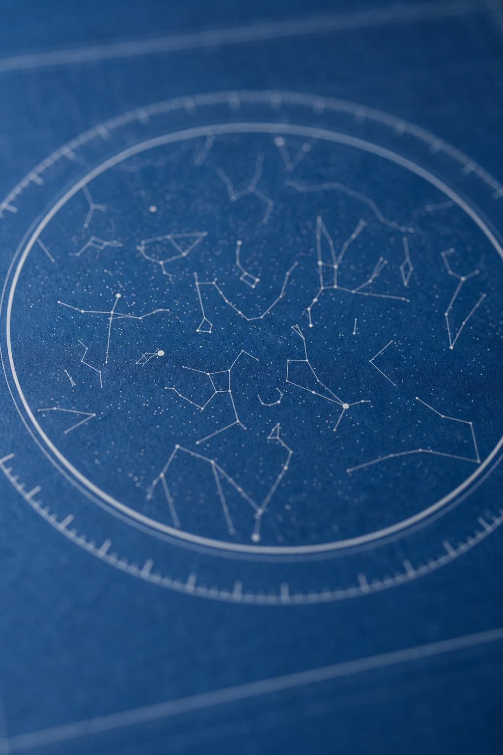A close-up of a blue star map print showing white constellation lines inside a thin circular ring.