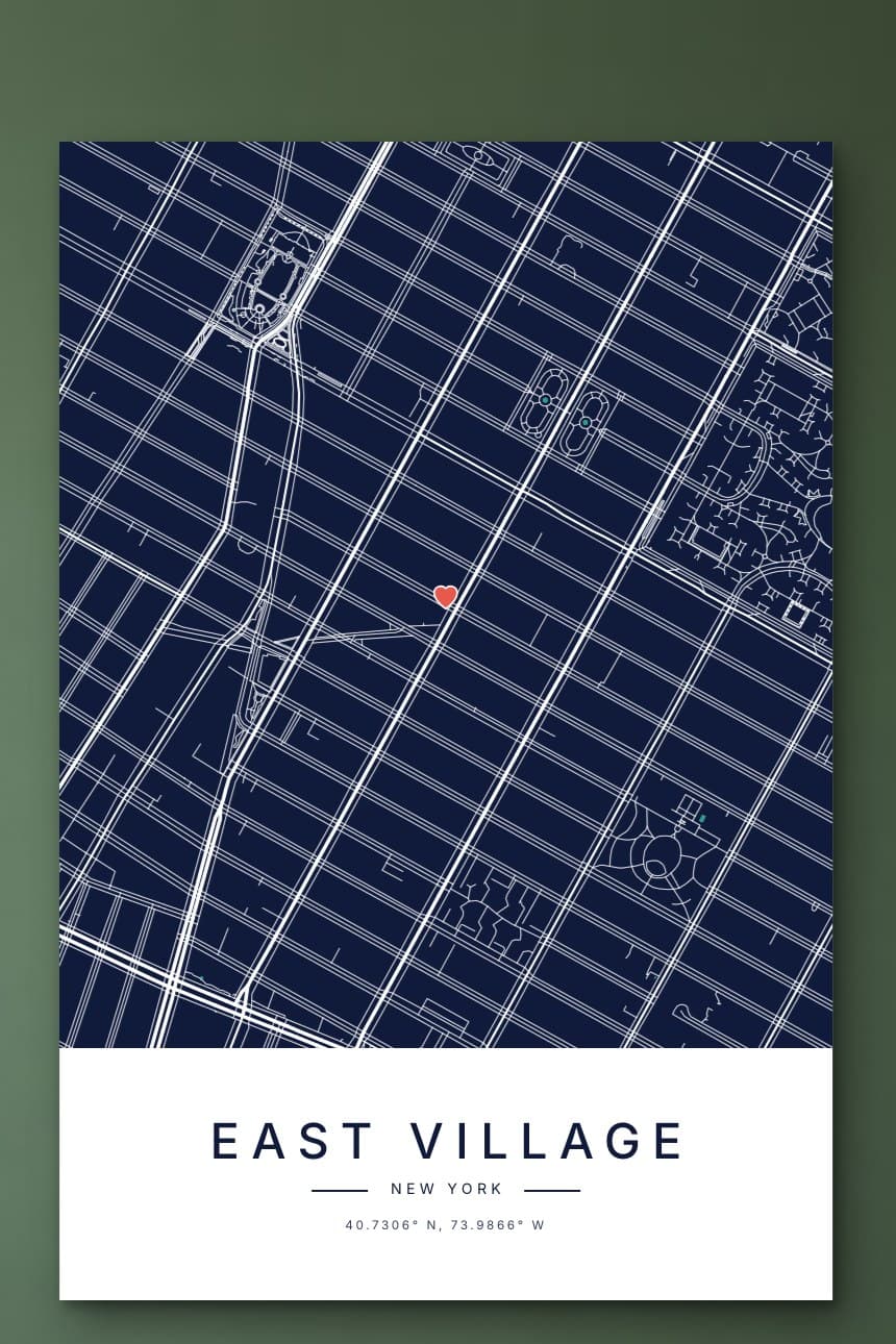 A navy city map poster of New York's East Village street grid with a small heart, hanging on a sage green wall.