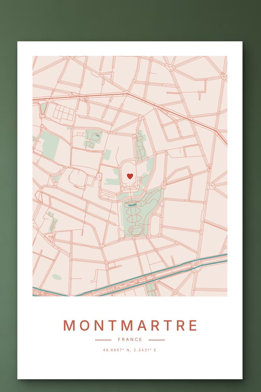 A peach and rose city map poster of Montmartre with a small red heart near Sacré-Cœur, hanging on a sage green wall.